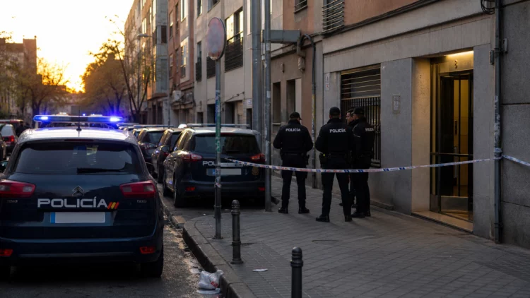 Imagen ilustrativa de un operativo policial junto a un portal de viviendas en una calle de barrio.