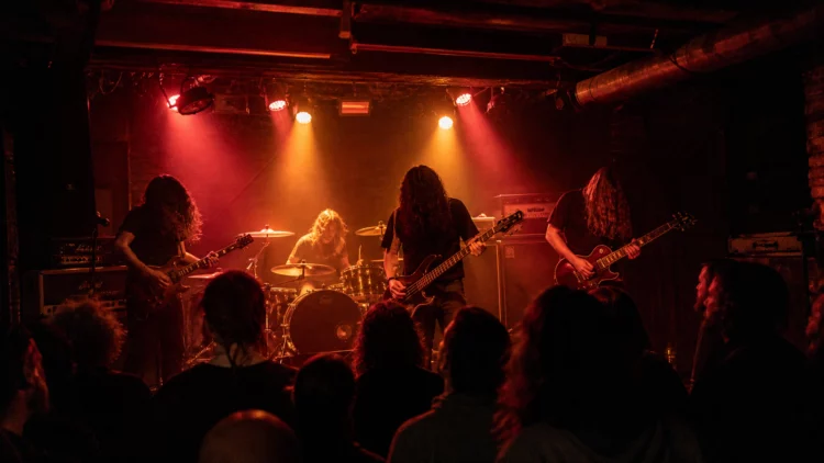 Concierto de rock pesado en una sala pequeña con luces rojas y público frente al escenario