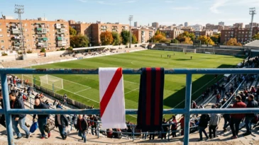 Bufandas con la franja roja del Rayo y los colores del Cagliari ante un campo de fútbol
